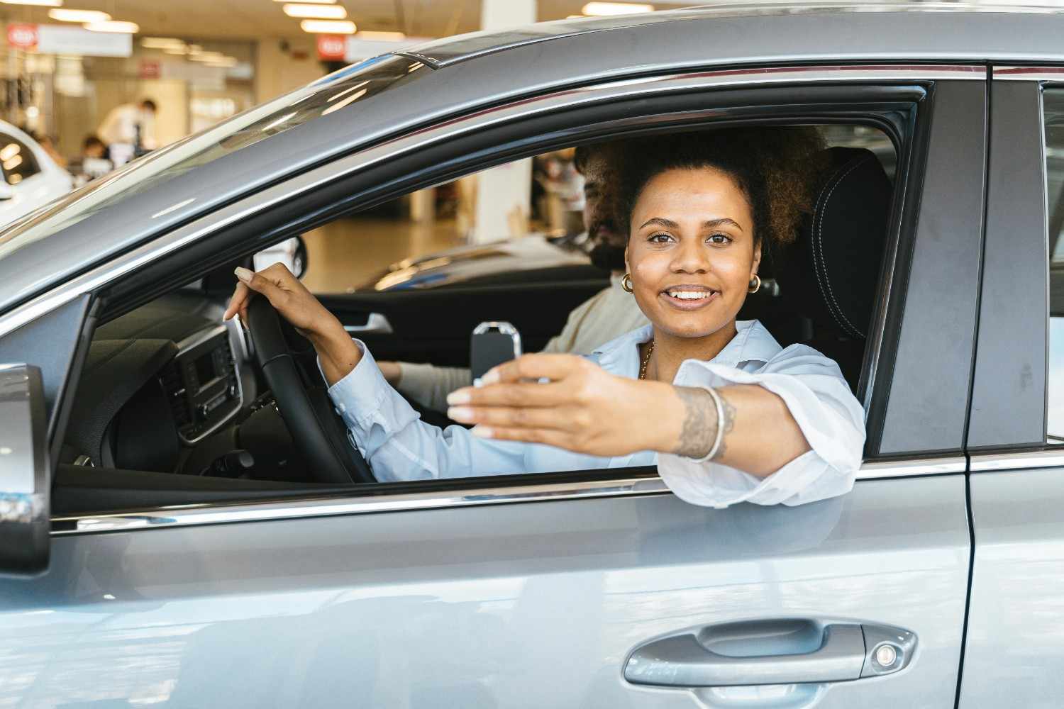A professional woman smiling while holding her car keys in front of a white SUV